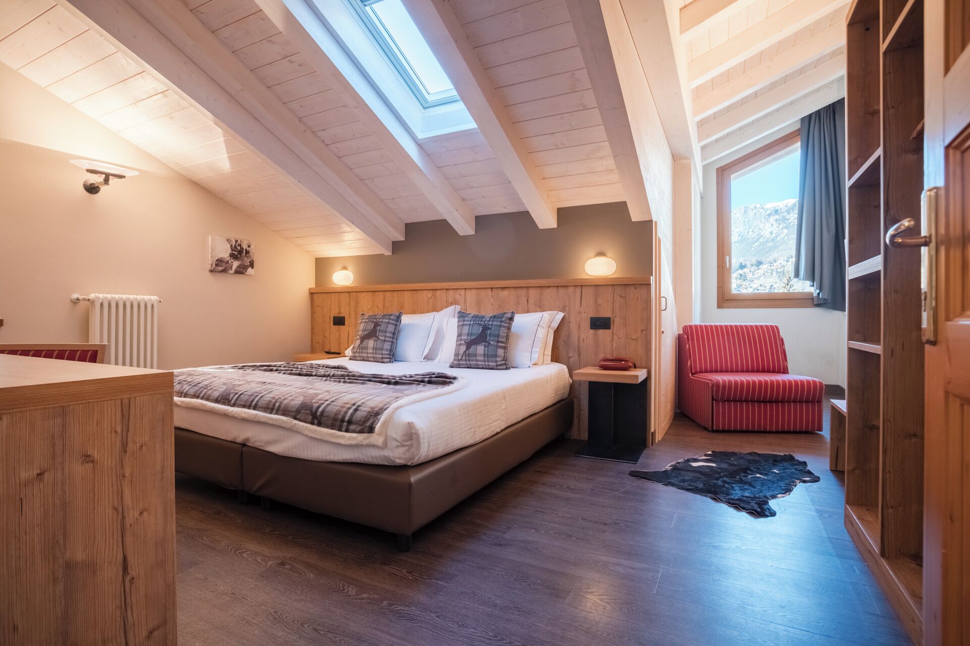 Een slaapkamer met een groot bed, een houten hoofdbord en een dakraam.