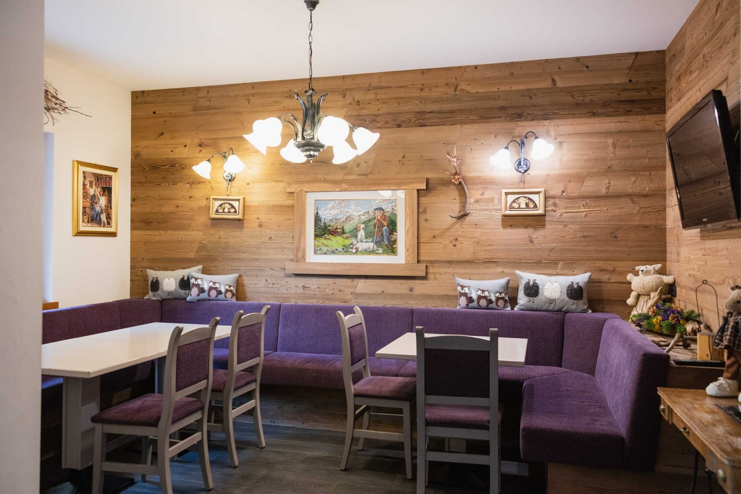 Un rincón comedor acogedor con una pared de madera, asientos morados y una araña.