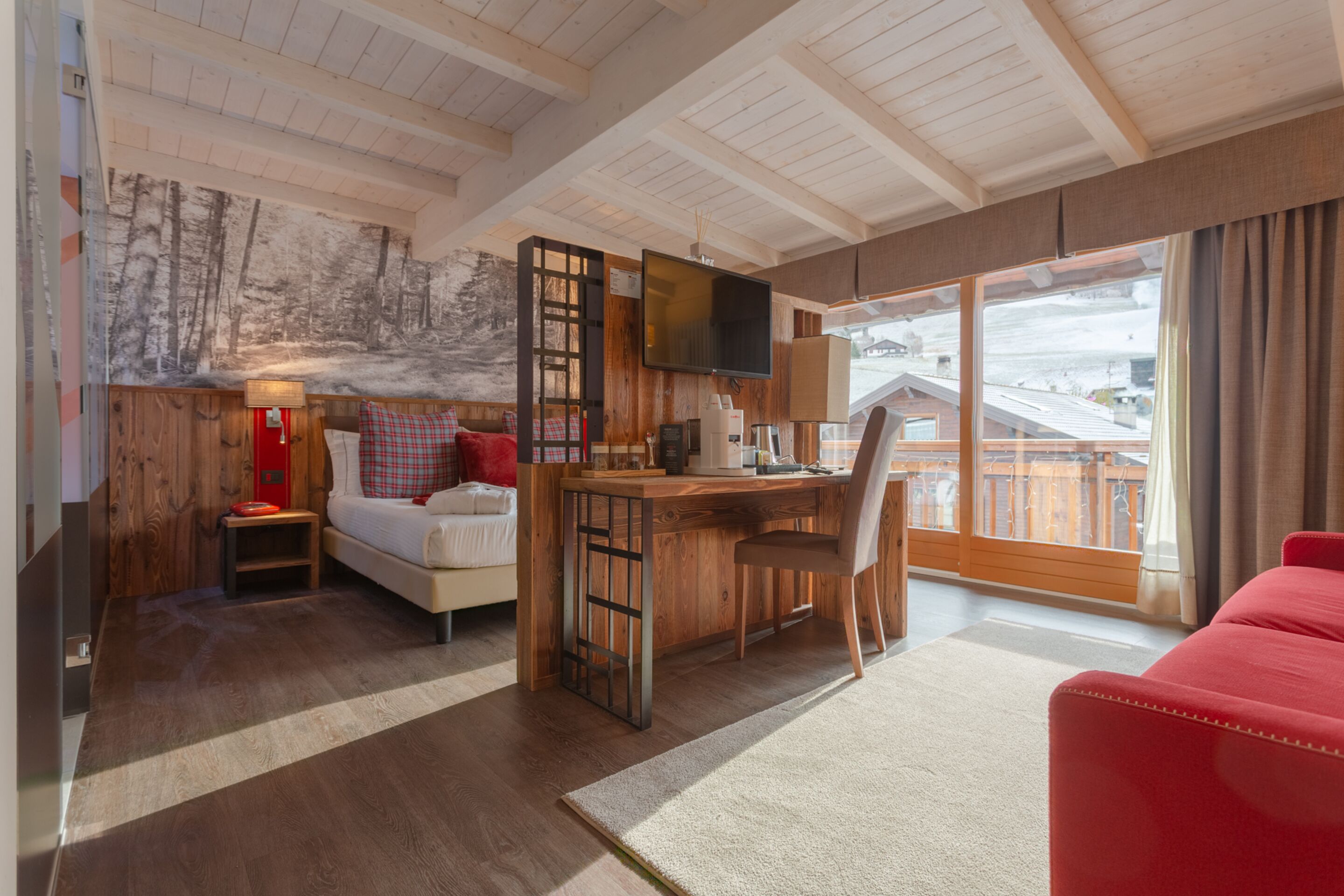A cozy room with a bed, a desk, and a red couch.