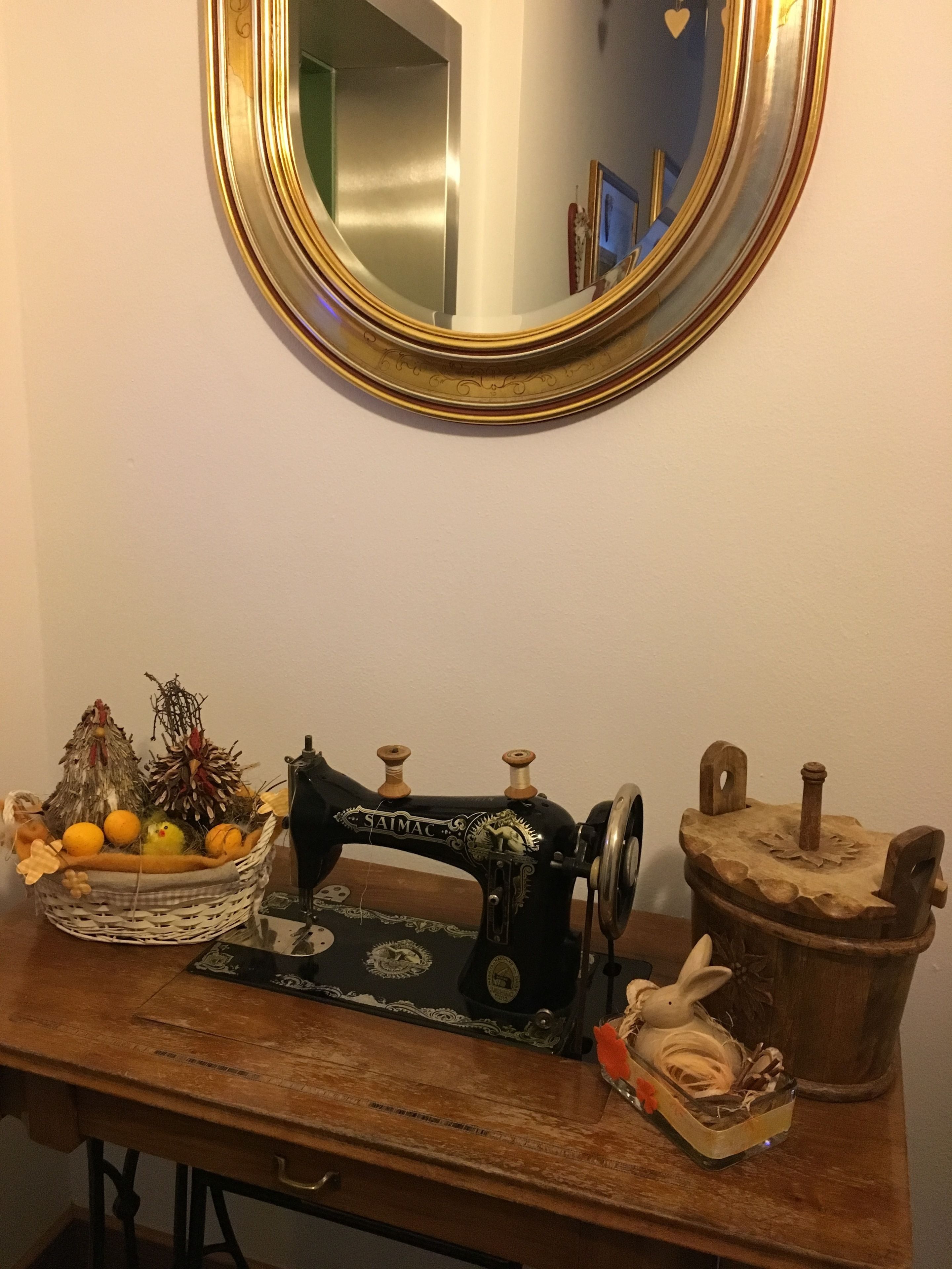 A vintage sewing machine on a wooden table with a mirror above it.