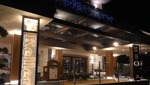 A hotel entrance with a neon sign, a reception desk, and a glass facade. - Olimpia Hotel (Bormio)