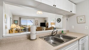 A kitchen with a large mirror, a sink, and a window overlooking a balcony. - Endless Ocean Views in S Fletcher Duplex by RedAwning (Fernandina Beach)