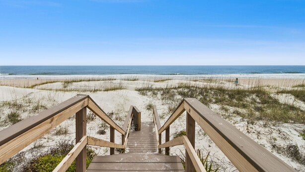 A wooden staircase leading to a beach with a clear sky. - Endless Ocean Views in S Fletcher Duplex by RedAwning (Fernandina Beach)