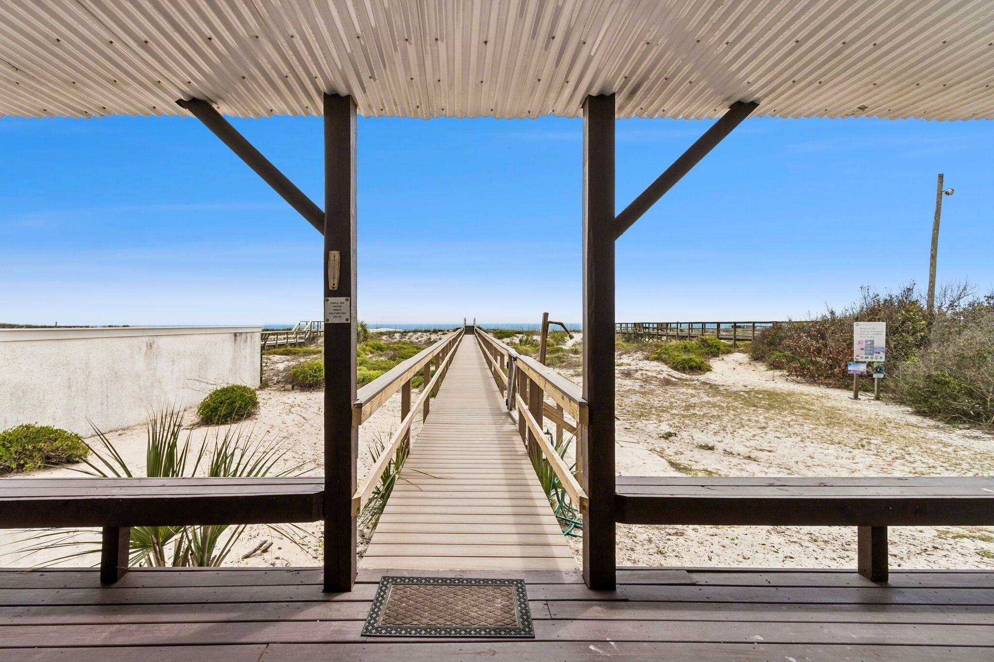 Une promenade en bois menant à une plage, avec un espace d’observation abrité.