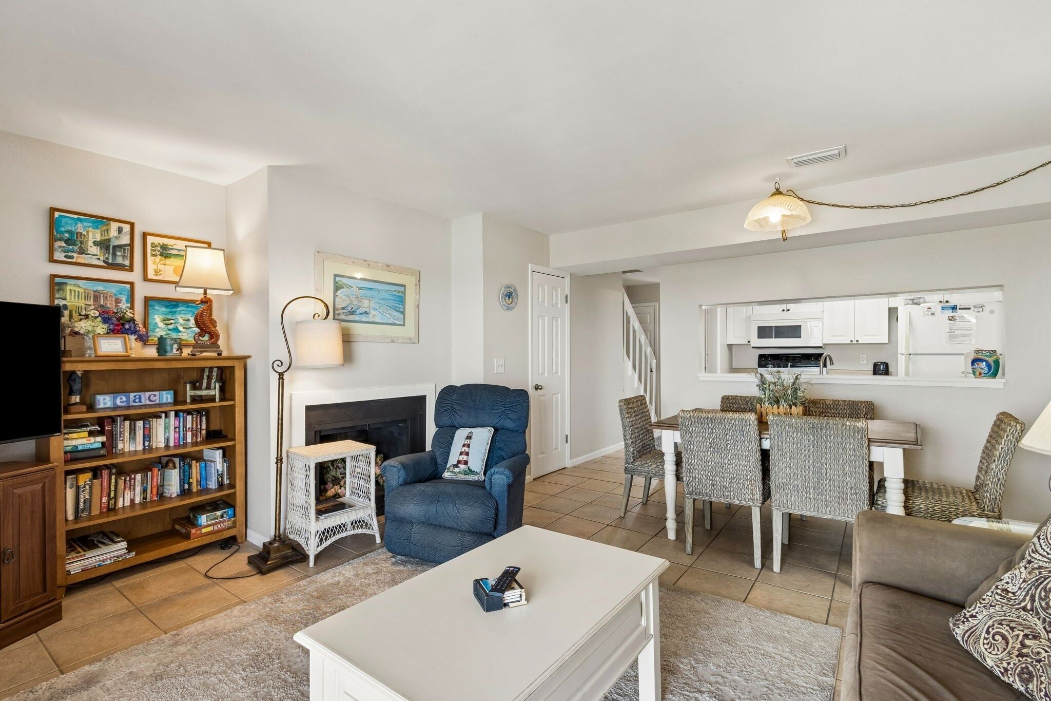 A living room with a fireplace, a bookshelf, a television, and a dining area with chairs and a table.