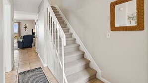 A staircase with carpeted steps and white railings, a wall-mounted mirror, and a door leading to a room with a view. - Relaxed Atmosphere in S Fletcher Duplex by RedAwning (Fernandina Beach)