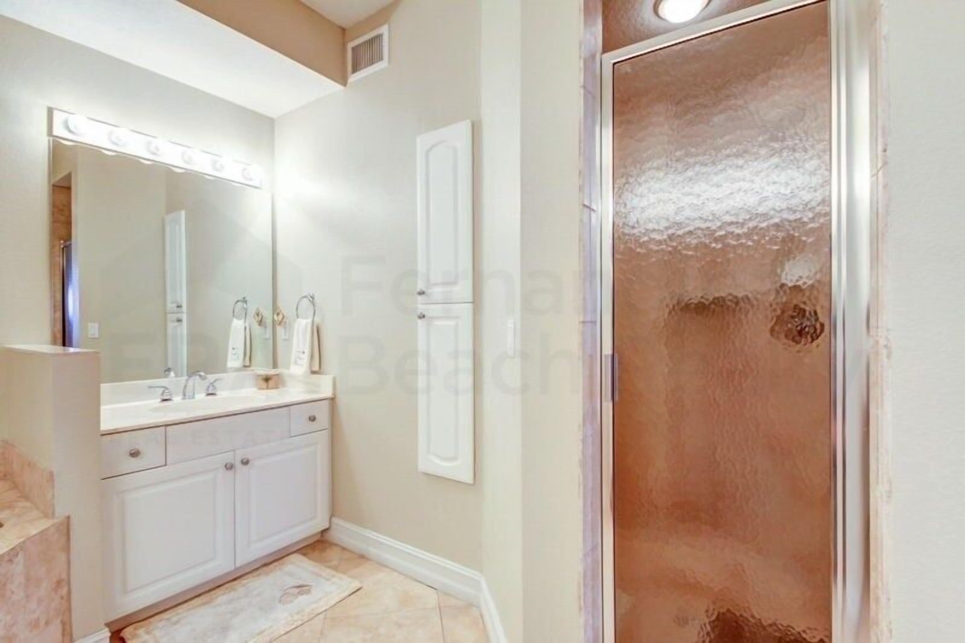 A bathroom with a vanity, mirror, and shower.