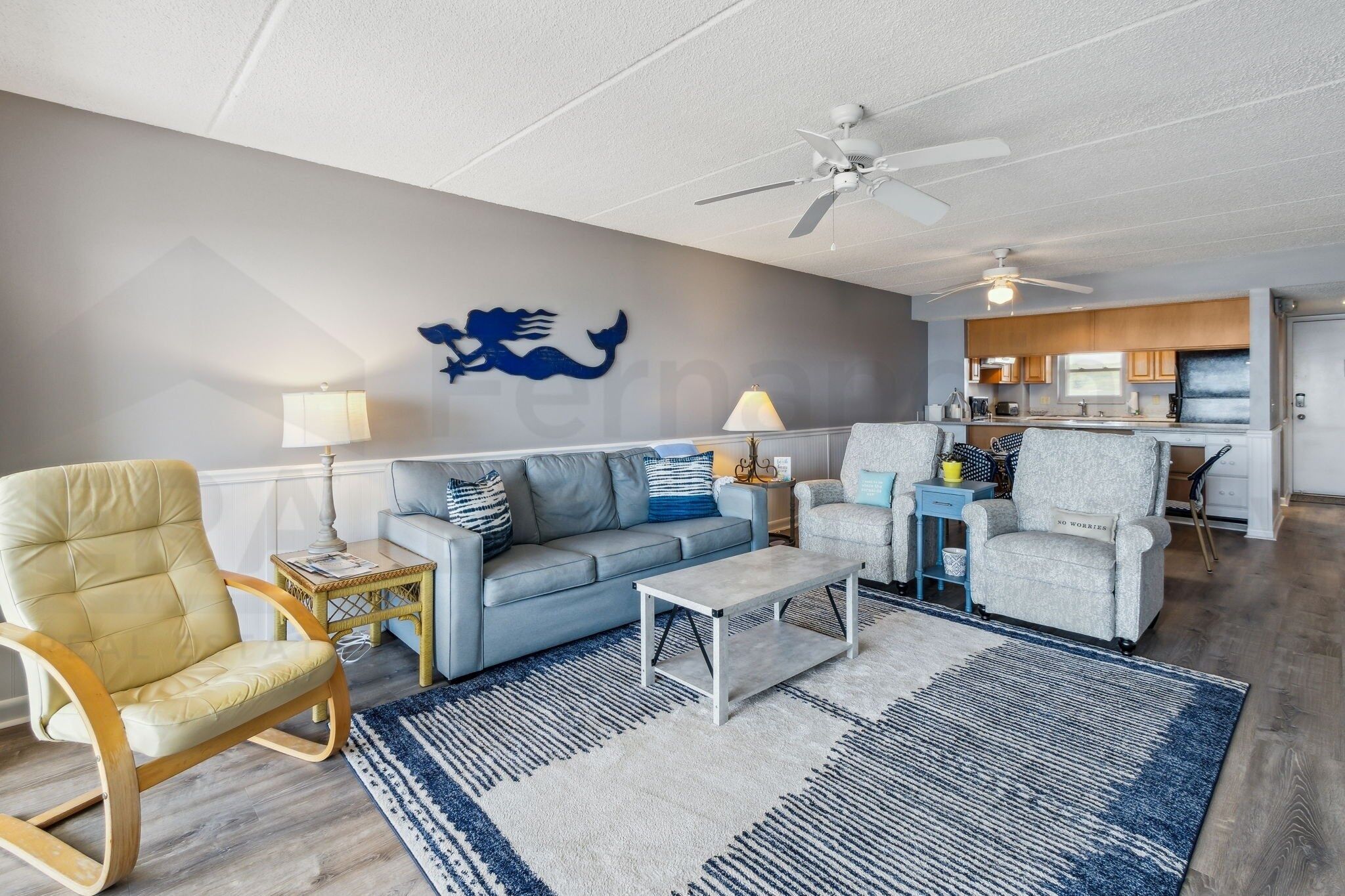 A modern living room with a sofa, armchairs, a coffee table, and a rug.