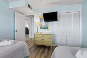 A hotel room with two beds, a television, a dresser, and a mirror. - Striking Ocean View Condo with Private Walkway to the Beach by RedAwning (Fernandina Beach)