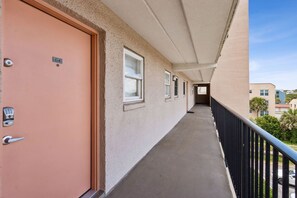 A corridor with a door labeled 'C-4', windows, and a black railing. - Striking Ocean View Condo with Private Walkway to the Beach by RedAwning (Fernandina Beach)