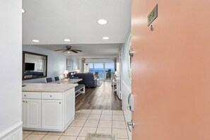 A spacious living area with a large window, a ceiling fan, and a dining table.