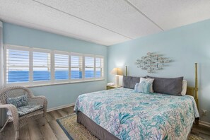 A bedroom with a bed, a chair, a nightstand, a lamp, and a wall decoration.