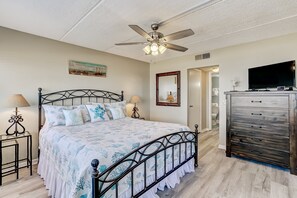 A bedroom with a bed, a ceiling fan, a dresser, and a television. - Enhanced Unit with Awesome View of Atlantic from Private Balcony by RedAwning (Fernandina Beach)