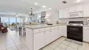 A spacious kitchen with white cabinetry, a black oven, and a large island with seating. - Condo with Atlantic View from Private Patio, Short Walk to the Beach by RedAwning (Fernandina Beach)
