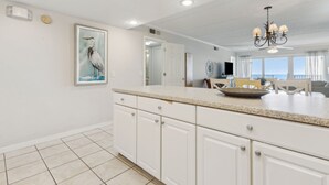 A kitchen with white cabinets, a granite countertop, and a chandelier. - Condo with Atlantic View from Private Patio, Short Walk to the Beach by RedAwning (Fernandina Beach)