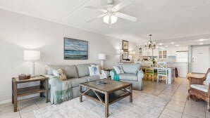 A spacious living room with a large sofa, coffee table, and dining area. - Condo with Atlantic View from Private Patio, Short Walk to the Beach by RedAwning (Fernandina Beach)