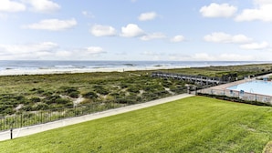 Vista de una playa con zona de piscina cercada y un paseo de madera que conduce a la playa.