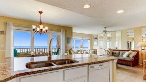 A kitchen with a large island, white cabinetry, and a view of the ocean.