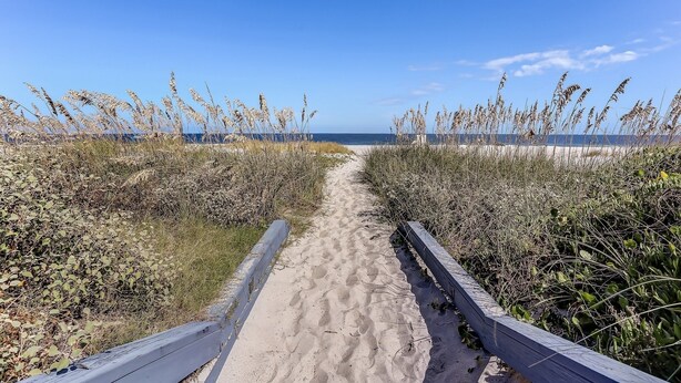 A sandy pathway flanked by tall grasses leading to the beach. - Modern Condo with Amazing Ocean Front Views by RedAwning (Fernandina Beach)