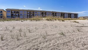 A beachfront hotel with multiple balconies, a sandy beach in the foreground, and clear skies. - Modern Condo with Amazing Ocean Front Views by RedAwning (Fernandina Beach)