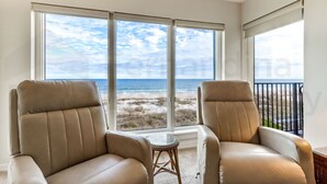 A room with two leather chairs, a small round table, and a large window offering a view of the beach and ocean. - Beautifully Decorated Condo with Magnificent View of Atlantic by RedAwning (Fernandina Beach)