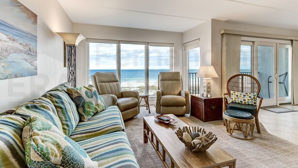A spacious living room with a large window overlooking the ocean, a ceiling fan, and a comfortable seating area with a sofa and chairs. - Beautifully Decorated Condo with Magnificent View of Atlantic by RedAwning (Fernandina Beach)