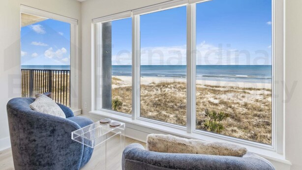 A room with large windows overlooking a beach.