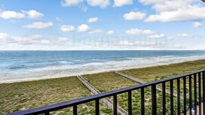 A coastal view from a balcony with a railing, a beach, and a clear sky. - Amelia South B7 by RedAwning (Fernandina Beach)