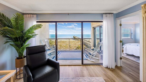 A room with a large sliding glass door leading to a balcony with a view of the beach. - Tastefully Decorated Condo with Scenic Beach Views by RedAwning (Fernandina Beach)