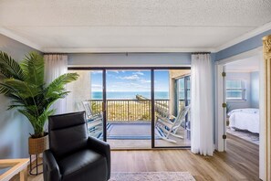 A room with a large sliding glass door leading to a balcony with a view of the beach. - Tastefully Decorated Condo with Scenic Beach Views by RedAwning (Fernandina Beach)