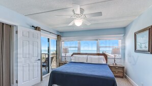 A bedroom with a bed, a ceiling fan, a window, and a door leading to a balcony. - Upper unit Overlooking the Beautiful Outdoor Space and Pier by RedAwning (Fernandina Beach)