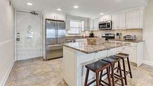 A modern kitchen with white cabinets, stainless steel appliances, and a granite countertop. - Upper unit Overlooking the Beautiful Outdoor Space and Pier by RedAwning (Fernandina Beach)