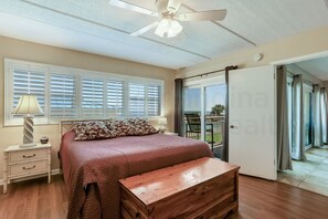 Relax in this serene bedroom with a large bed, ceiling fan, and sliding glass door leading to an outdoor space.