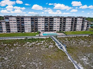 A multi-story residential building with a swimming pool and a landscaped area. - Comfy Upper Unit Condo to Enjoy the Beach or the Fishing by RedAwning (Fernandina Beach)