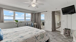 A bedroom with a bed, a ceiling fan, a TV, and a view of the ocean. - Oceanfront Condo with Beach Access, Pool, and Tennis Court by RedAwning (Fernandina Beach)