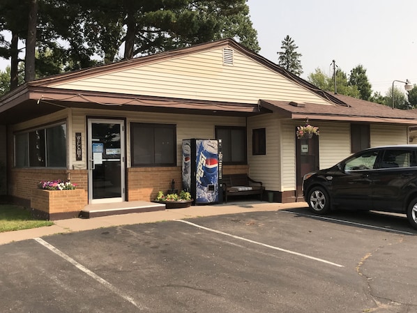 Un motel con un letrero de cerrado, un refrigerador de Pepsi y un coche estacionado en el estacionamiento.