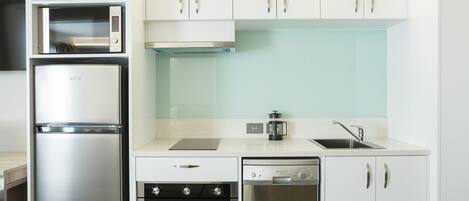 Una cocina moderna con un refrigerador de acero inoxidable, horno empotrado, lavavajillas y muebles de color blanco.