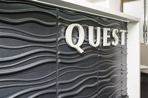 Una pared con textura y la palabra "QUEST" en letras grandes.
