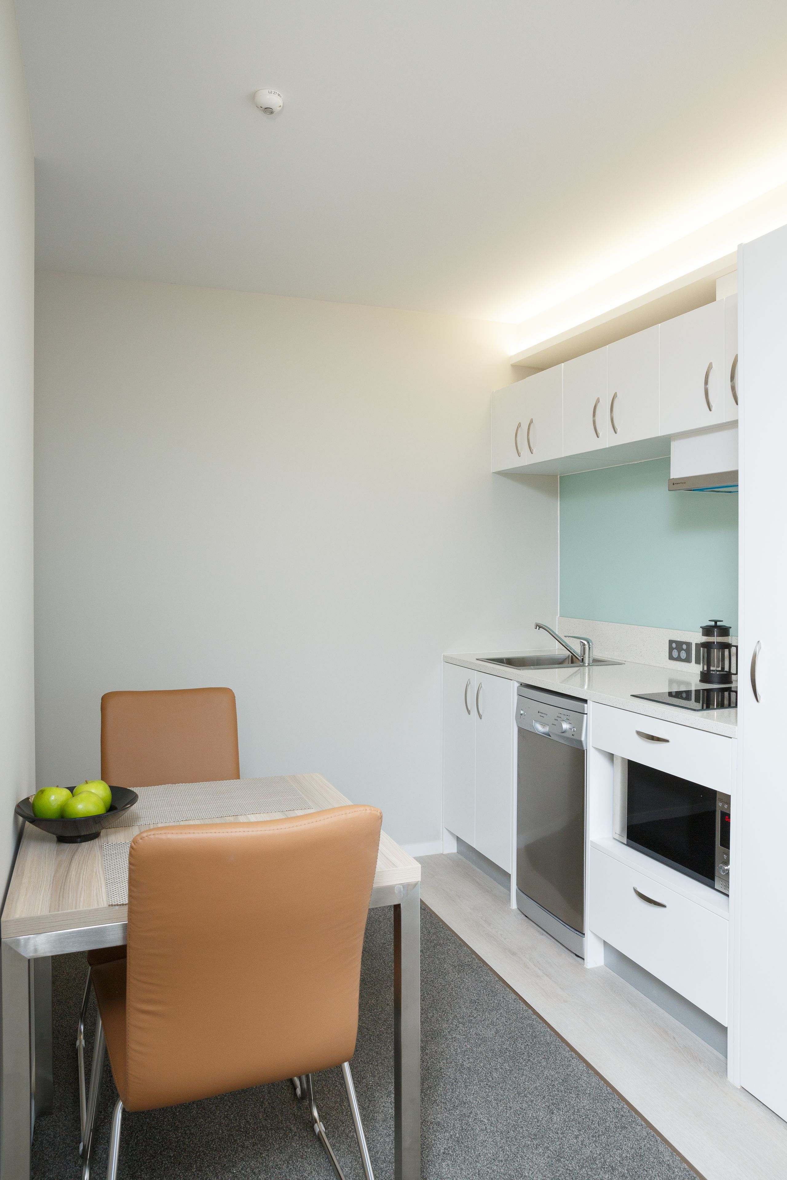 A modern kitchen with white cabinetry, a stainless steel sink, and a built-in oven.