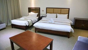 Habitación de hotel con dos camas, una mesita y un armario.