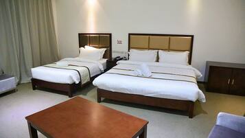 A hotel room with two beds, a small table, and a wardrobe.