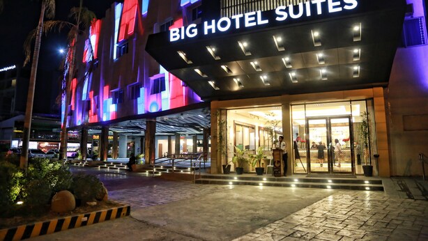 El exterior de un hotel con un letrero llamativo que dice "BIG HOTEL SUITES".