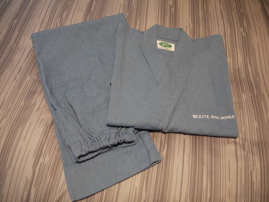 Una camisa gris doblada con un logotipo y texto que indica que pertenece a Route Inn Hotels.