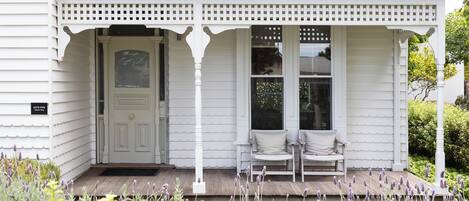 A white building with a porch, a door, and two windows.