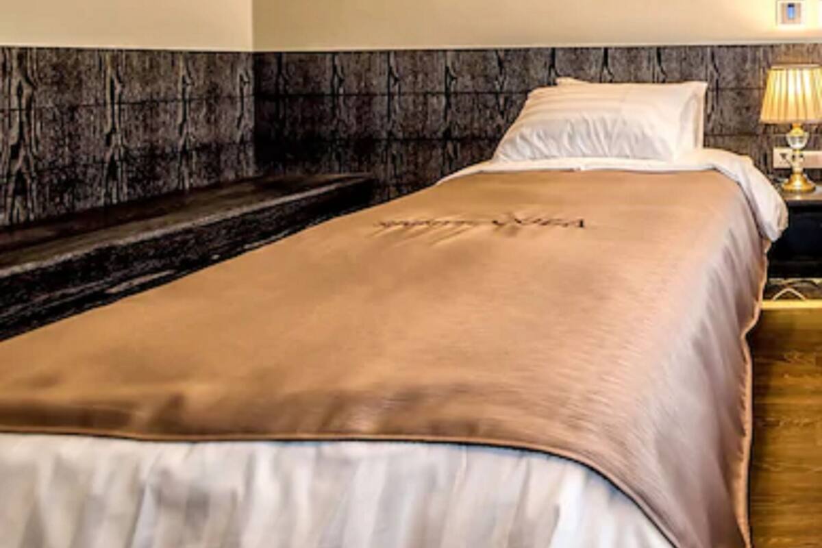 Een hotelkamer met een bed, nachtkastje en lamp.