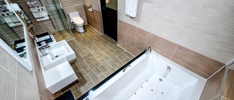 A modern bathroom with a large bathtub, two sinks, a toilet, and a shower area.