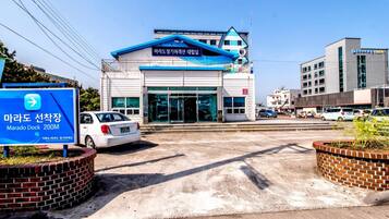 A building with a blue and white sign, a white car parked in front, and a clear sky.