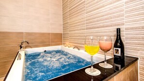 Una bañera con dos copas de vino y una botella sobre una encimera de madera.