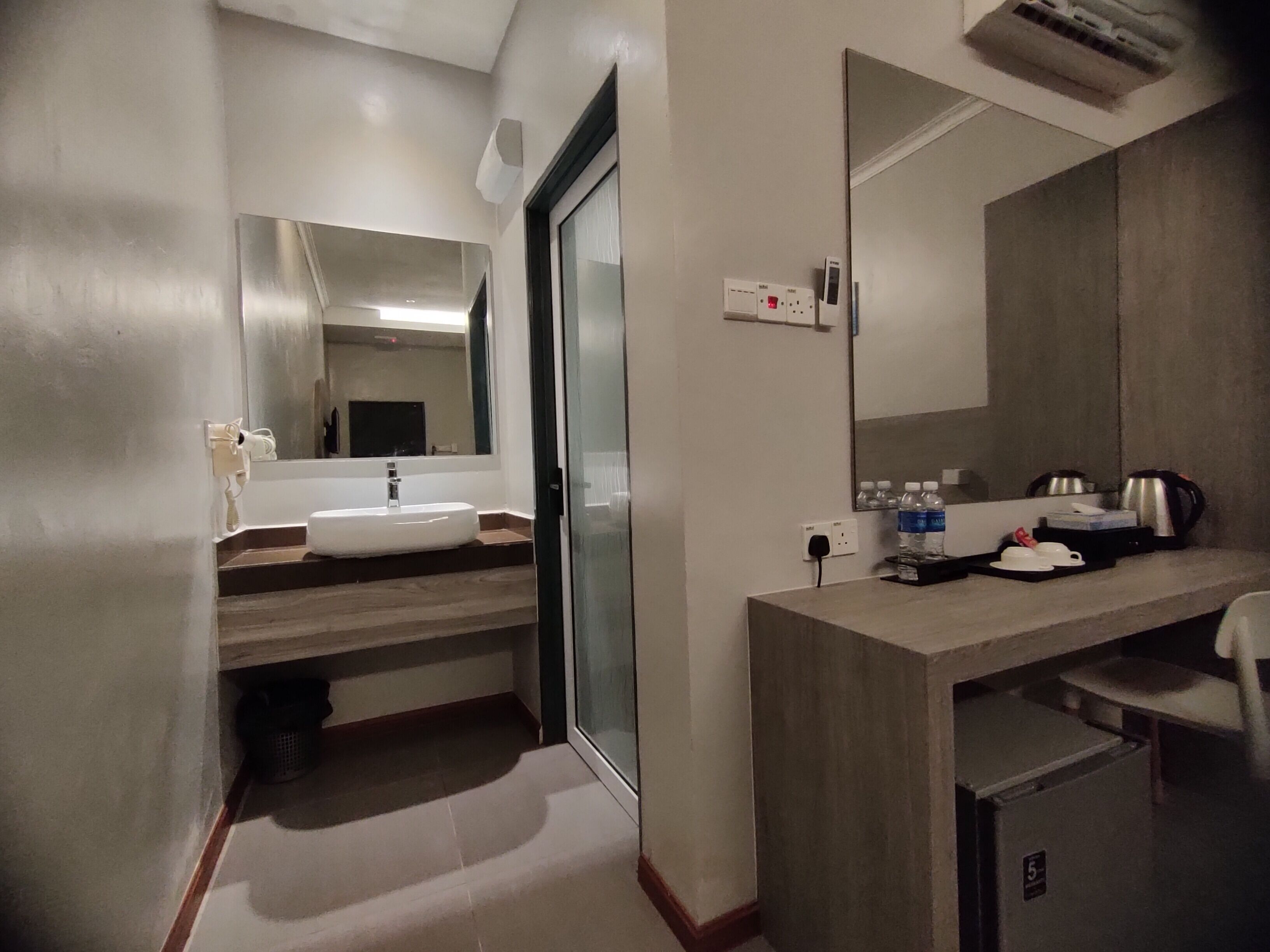 A modern bathroom with a sink, mirror, and a small refrigerator.