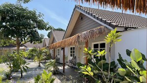 A tropical-style building with a tiled roof, a thatched roof over the entrance, and a garden with various plants and flowers. - Lavigo Resort (Langkawi)